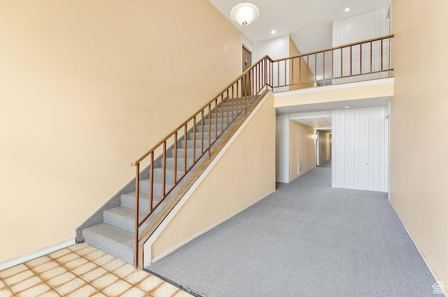 stairway featuring a high ceiling and carpet floors