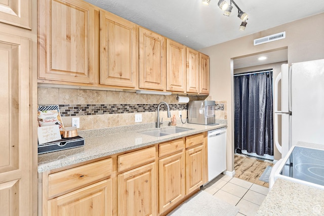 kitchen featuring a sink, light brown cabinetry, white appliances, light tile patterned floors, and backsplash