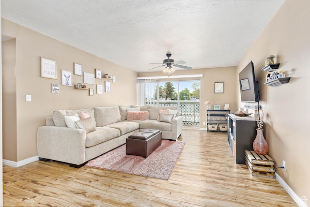 living room featuring light wood-style floors, ceiling fan, baseboards, and a textured ceiling