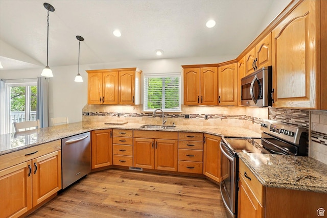 kitchen with appliances with stainless steel finishes, a sink, healthy amount of natural light, light stone countertops, and recessed lighting