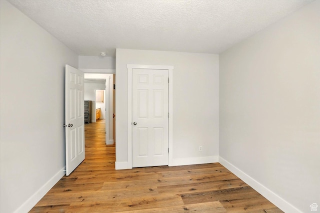 unfurnished bedroom with light wood-style flooring, baseboards, and a textured ceiling