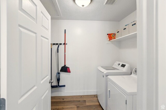 laundry area featuring washer and clothes dryer, wood finished floors, baseboards, and a textured ceiling