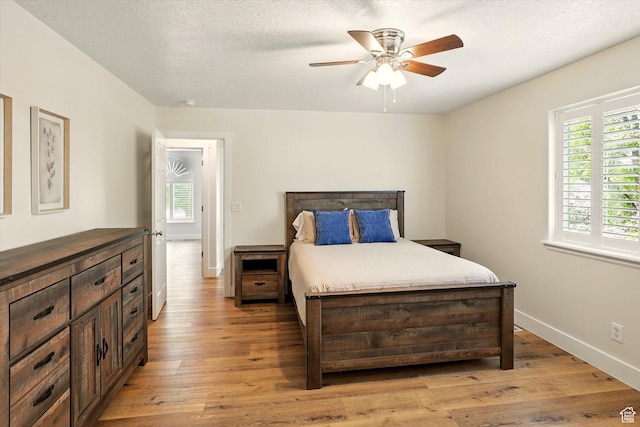 bedroom featuring light wood-style floors, baseboards, and a ceiling fan