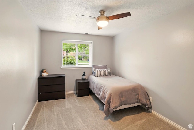 bedroom featuring carpet floors, a textured ceiling, baseboards, and a ceiling fan