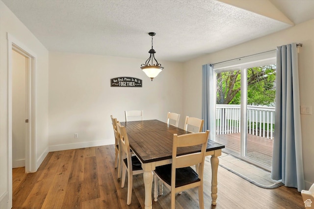 dining area with light wood-style floors, baseboards, and a textured ceiling