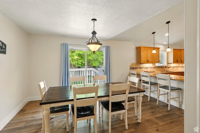 dining area with a textured ceiling, dark wood finished floors, and baseboards