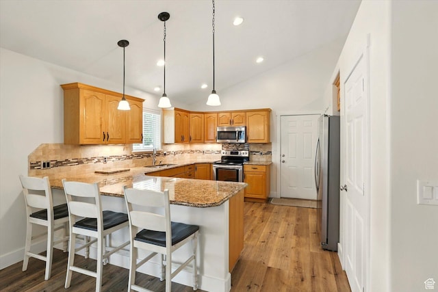 kitchen featuring stainless steel appliances, a peninsula, a sink, backsplash, and light stone counters