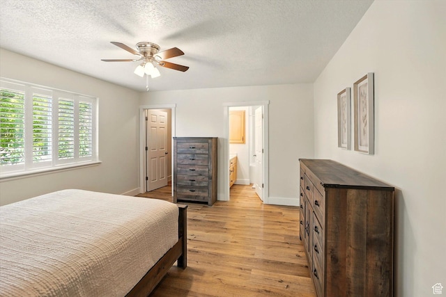 bedroom with light wood-type flooring, baseboards, ensuite bathroom, a ceiling fan, and a textured ceiling