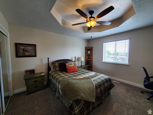 carpeted bedroom with baseboards, a tray ceiling, a ceiling fan, and a textured ceiling