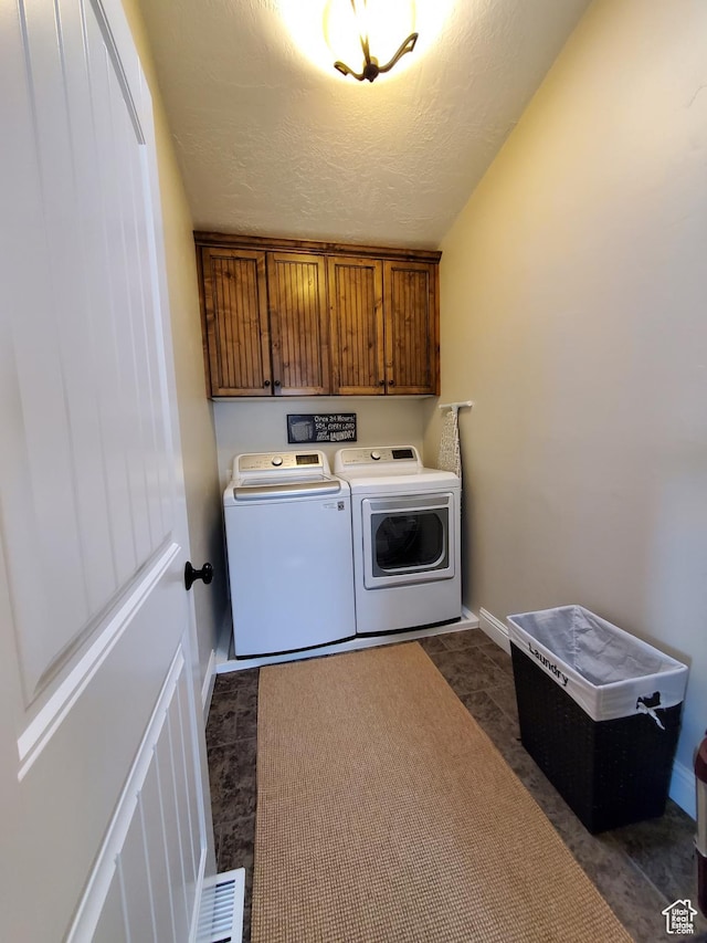laundry area with cabinet space, washing machine and clothes dryer, a textured ceiling, and baseboards