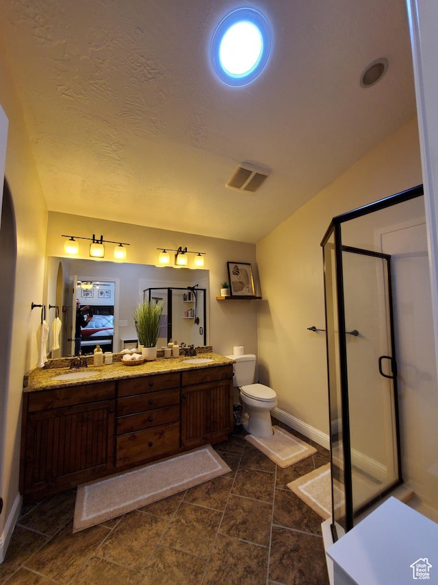 ensuite bathroom featuring baseboards, a shower stall, toilet, and double vanity