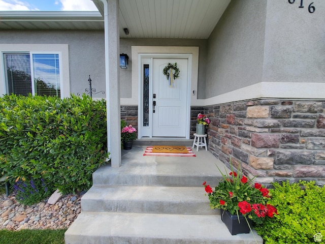doorway to property featuring stucco siding and stone siding