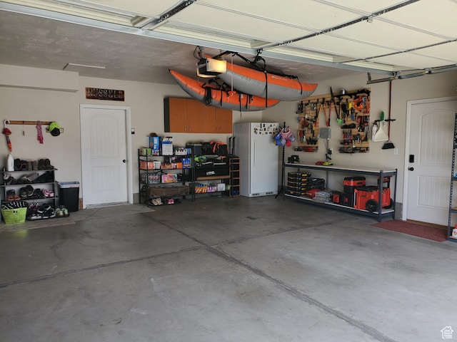 garage featuring freestanding refrigerator, a garage door opener, and a workshop area