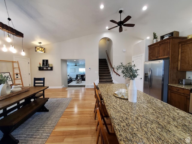 dining area featuring ceiling fan, stairs, light wood-type flooring, arched walkways, and baseboards