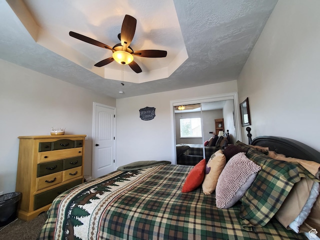 carpeted bedroom featuring a raised ceiling and ceiling fan