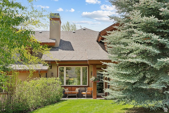rear view of property featuring an outdoor hangout area, roof with shingles, a yard, a chimney, and stucco siding