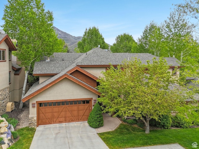 view of front of house with stucco siding, roof with shingles, stone siding, and driveway