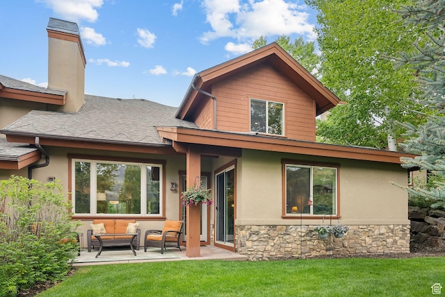 rear view of house with outdoor lounge area, a lawn, a chimney, and stone siding