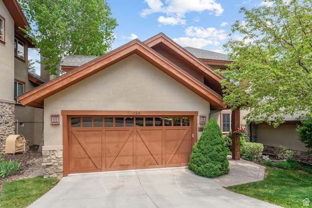 view of front of house featuring stucco siding, an attached garage, driveway, and stone siding