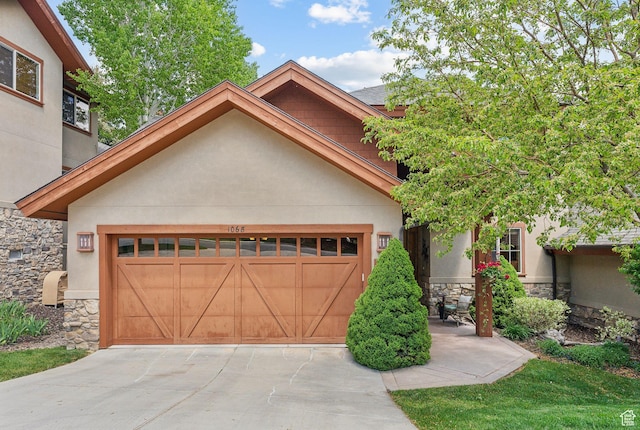 view of front of home with stone siding, stucco siding, an attached garage, and driveway