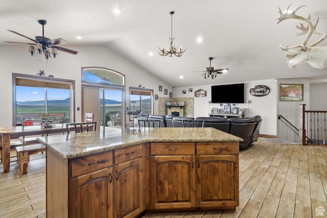 2521 W Ridgeline Rd, Stockton, UT 84071 - kitchen with ceiling fan, light wood finished floors, a fireplace, a center island, and light stone countertops