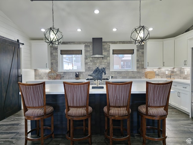 123 Red Hawk Ave, Evanston, WY 82930 - kitchen with wall chimney range hood, healthy amount of natural light, backsplash, a center island with sink, and recessed lighting