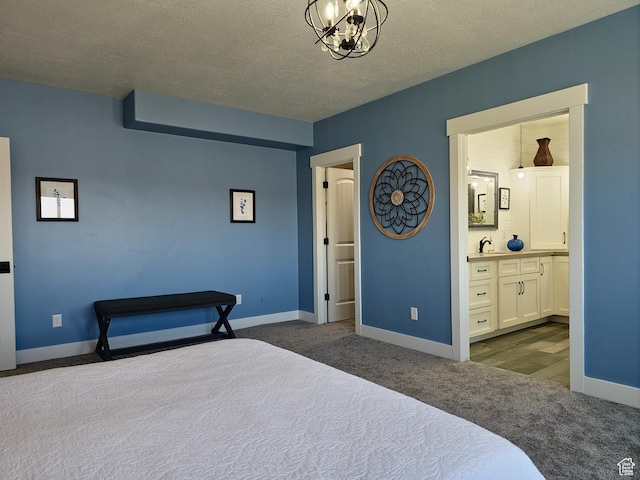123 Red Hawk Ave, Evanston, WY 82930 - bedroom featuring dark carpet, a chandelier, baseboards, connected bathroom, and a textured ceiling