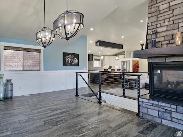 123 Red Hawk Ave, Evanston, WY 82930 - recreation room with a chandelier, dark wood-style floors, a wainscoted wall, a stone fireplace, and lofted ceiling