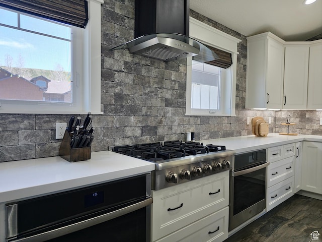 123 Red Hawk Ave, Evanston, WY 82930 - kitchen with stainless steel appliances, wall chimney range hood, backsplash, and light countertops