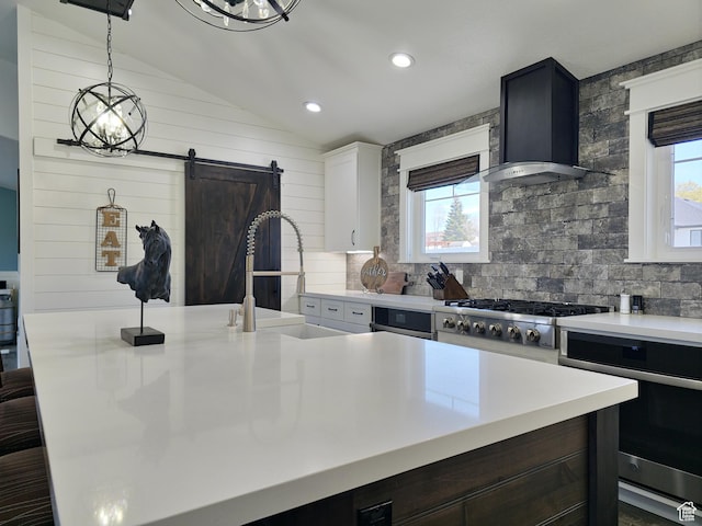 123 Red Hawk Ave, Evanston, WY 82930 - kitchen with appliances with stainless steel finishes, wall chimney exhaust hood, light countertops, lofted ceiling, and a barn door