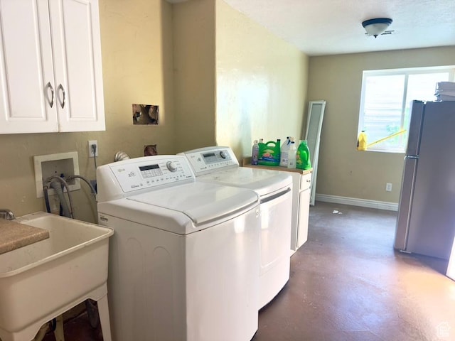 laundry area featuring washing machine and dryer, cabinet space, and baseboards