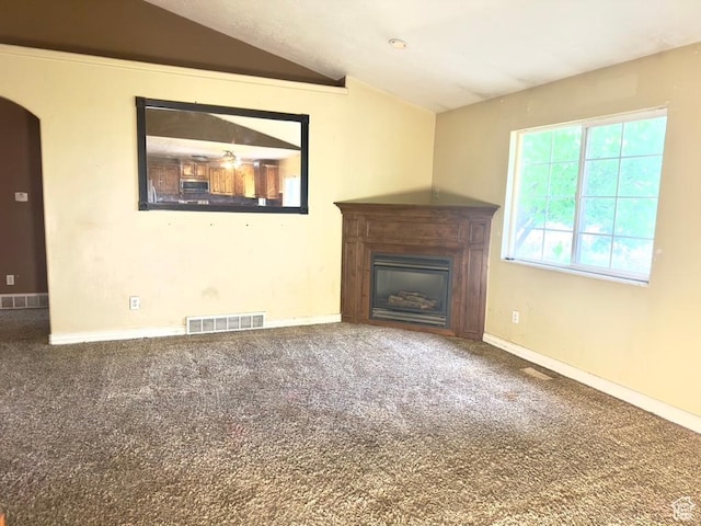 unfurnished living room featuring lofted ceiling, a glass covered fireplace, carpet floors, arched walkways, and baseboards