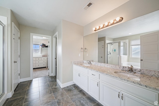 bathroom featuring a shower stall, baseboards, a walk in closet, double vanity, and a garden tub