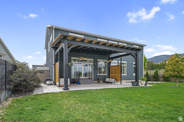 back of property featuring ceiling fan, a patio area, stucco siding, and a mountain view