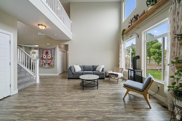 living area featuring a towering ceiling, wood finished floors, stairway, and plenty of natural light