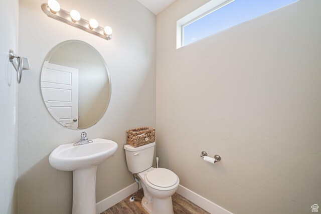 half bath featuring toilet, wood finished floors, and baseboards