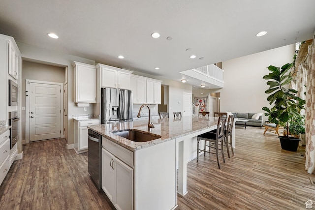 kitchen with a sink, stainless steel appliances, dark wood finished floors, recessed lighting, and a large island with sink