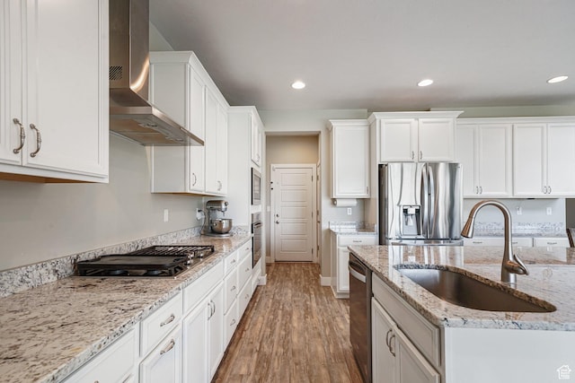 kitchen with stainless steel appliances, a sink, wall chimney range hood, wood finished floors, and recessed lighting