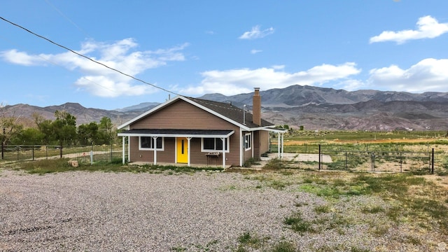1665 S Kennedy Dr, Marysvale, UT 84750 - view of front facade with a porch, a mountain view, fence, and a chimney