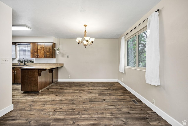 910 W 370 S, Logan, UT 84321 - kitchen with healthy amount of natural light, a chandelier, a breakfast bar area, and dark wood finished floors