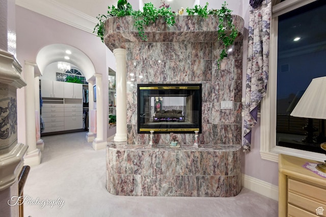 living room featuring ornate columns, crown molding, baseboards, and a tile fireplace