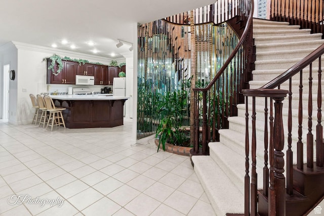 staircase featuring crown molding, tile patterned floors, and baseboards