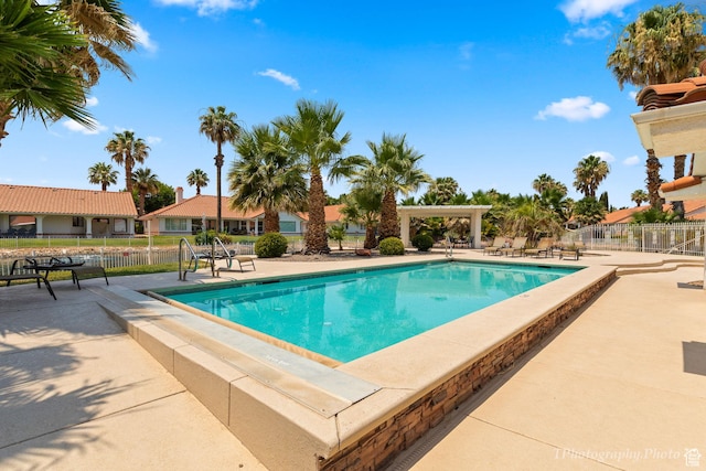 community pool with fence and a patio area