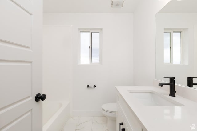 bathroom featuring toilet, vanity, marble look tile flooring, and baseboards