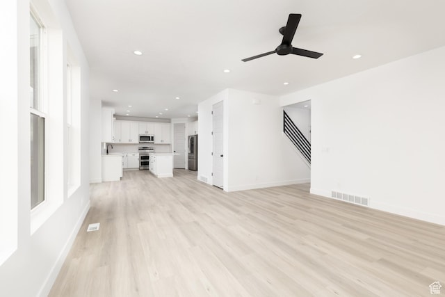 unfurnished living room with recessed lighting, light wood-style floors, ceiling fan, and baseboards