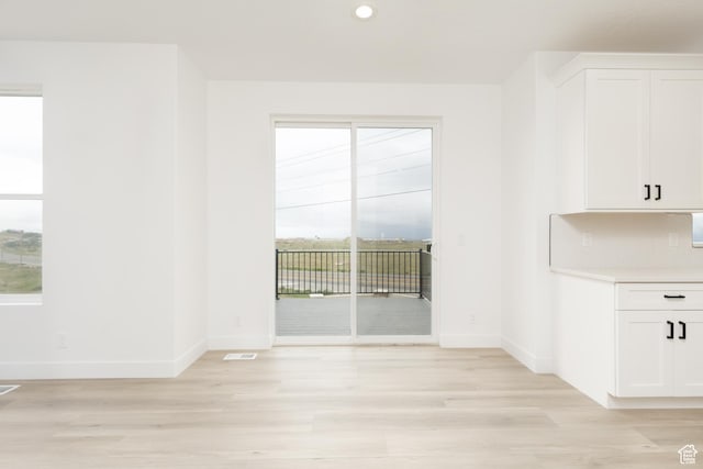 unfurnished dining area featuring baseboards, light wood-style flooring, and recessed lighting