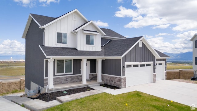 modern farmhouse style home with a porch, board and batten siding, a garage, and stone siding