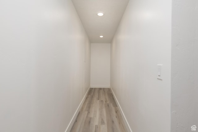 hallway featuring light wood-type flooring, recessed lighting, and baseboards