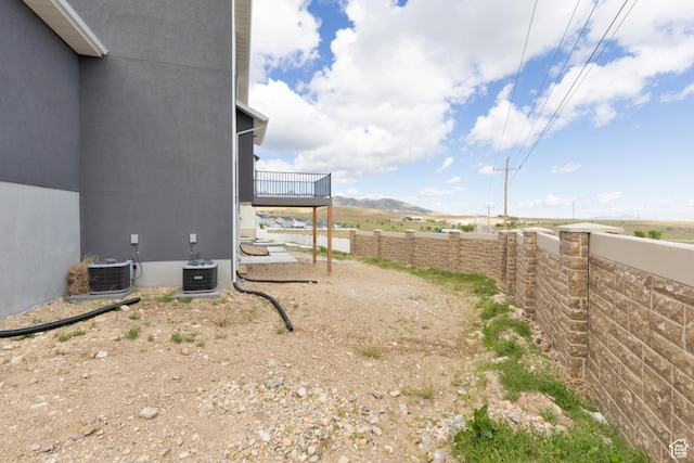 view of side of home with a fenced backyard, central air condition unit, and a wooden deck