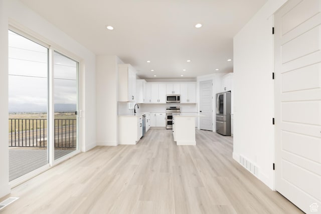 kitchen with appliances with stainless steel finishes, plenty of natural light, a sink, light wood-style flooring, and recessed lighting